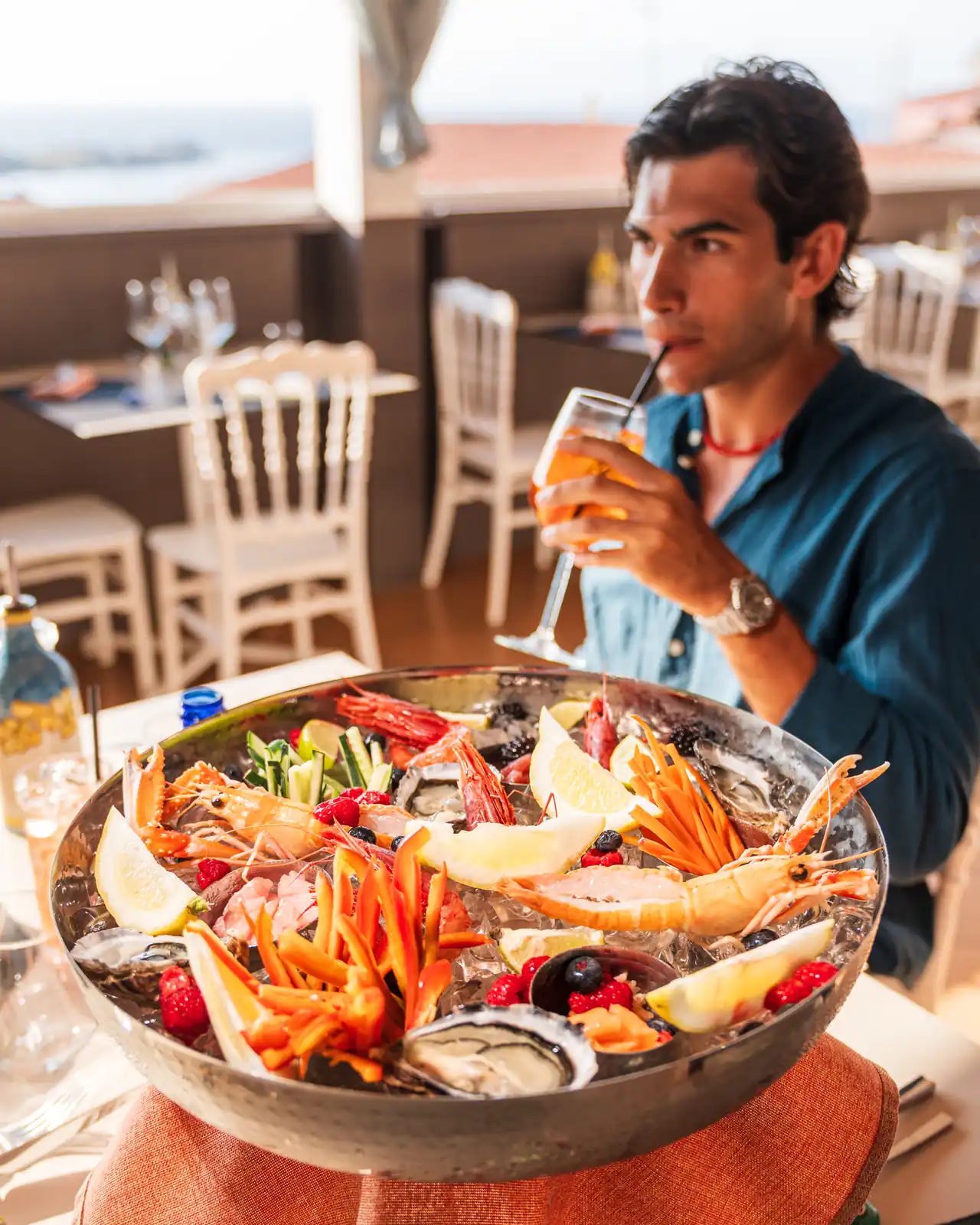 Il gran crudo su ghiaccio al tavolo, con la terrazza e il mare dietro