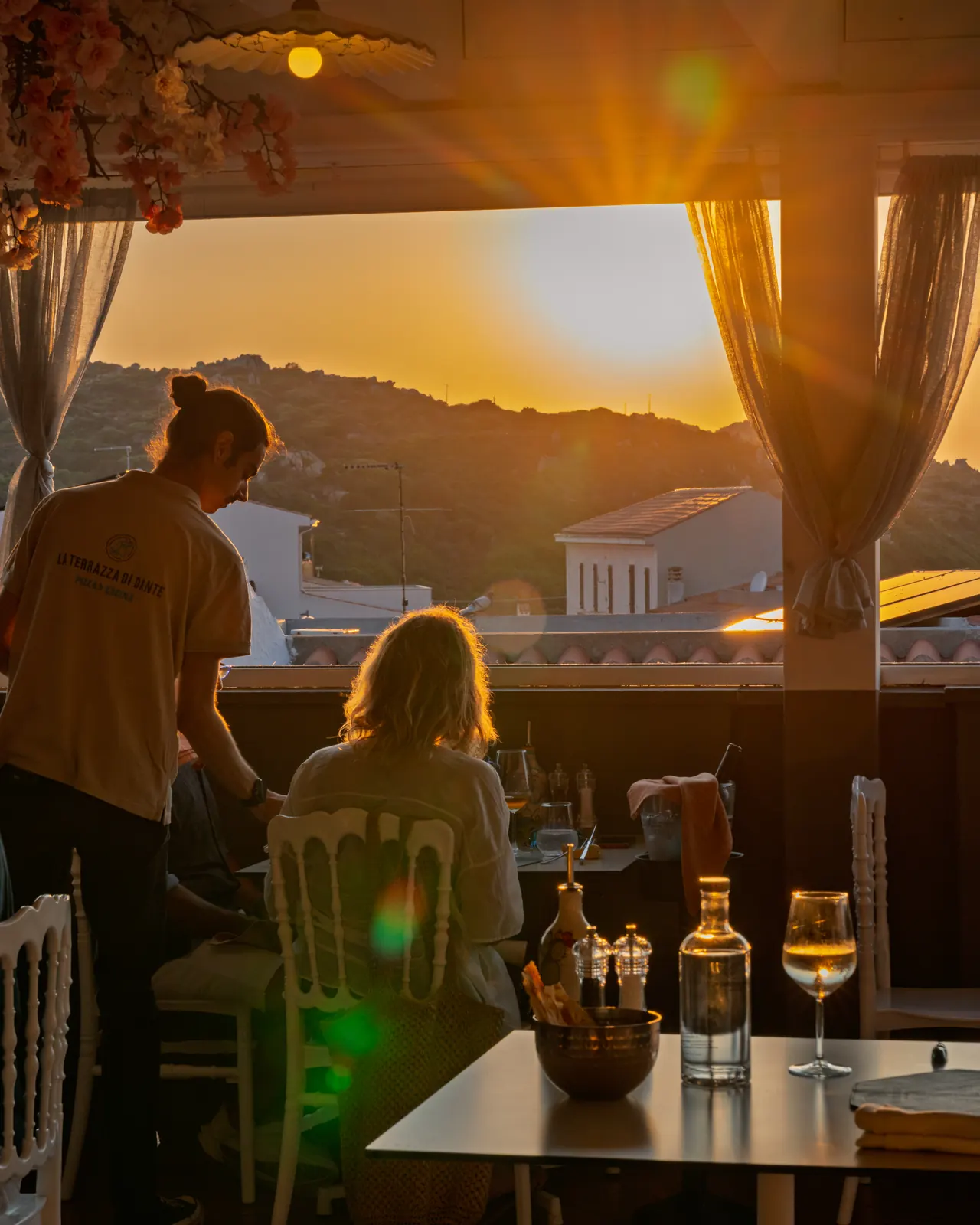 Gli ospiti a cena in terrazza mentre il sole tramonta